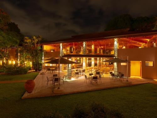 a patio with tables and chairs and umbrellas at night at Hotel Real Villa Bella in Ilhabela