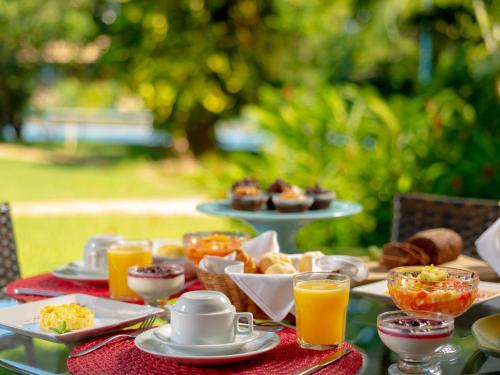 a table topped with plates of food and orange juice at Hotel Real Villa Bella in Ilhabela
