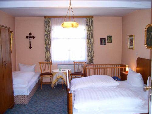 a bedroom with two beds and a table and a window at Hotel Krone in Gößweinstein