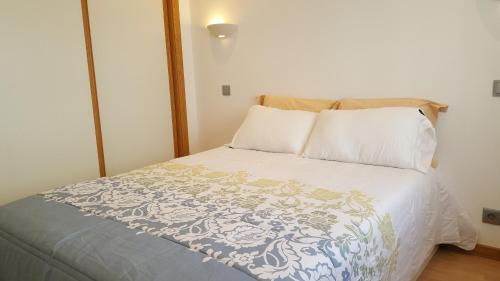 a bed with a blue and white blanket and pillows at Apartamento Cardoso II. A 5 minuto a pé da praia do Peneco in Albufeira