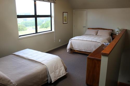 1 dormitorio con 2 camas, escritorio y ventana en The Loft at Te Kumi Tirohanga, en Te Kuiti