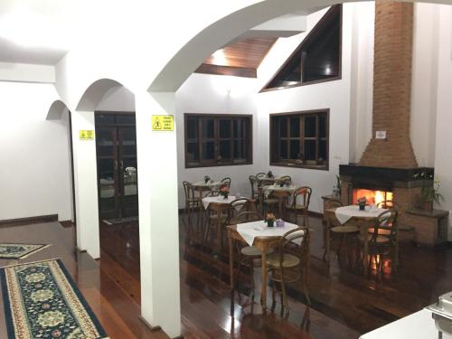 a dining room with tables and chairs and a fireplace at Pousada Casa Da Colina in Santo Antônio do Pinhal