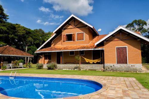 a house with a swimming pool in front of it at Pousada Casa Da Colina in Santo Antônio do Pinhal