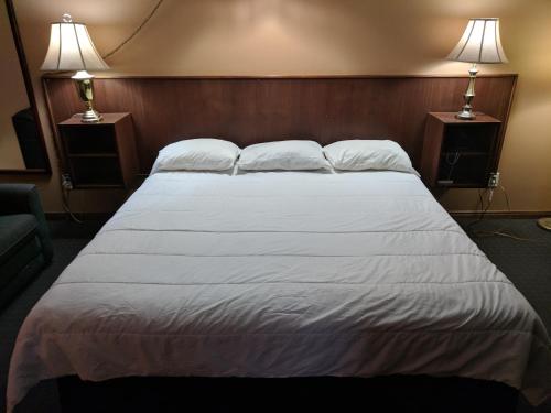 a large bed in a hotel room with two lamps at Bavarian Inn in Bruce Mines