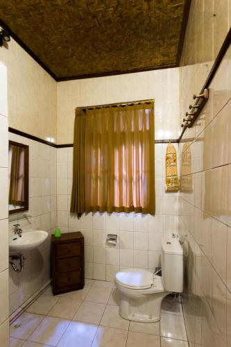 a bathroom with a toilet and a sink at Bali Asli Lodge by EPS in Ubud