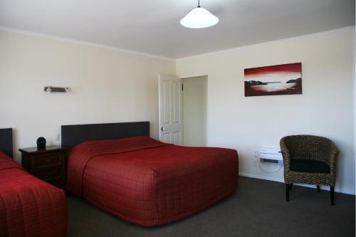 Habitación de hotel con cama roja y silla en Mount Hutt Motels, en Methven