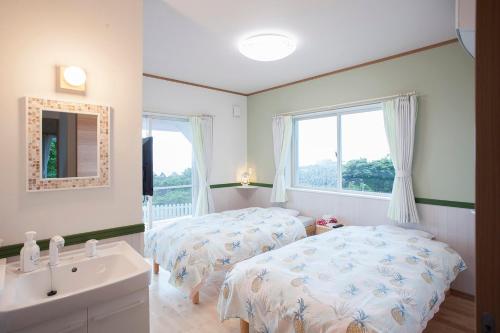 a bedroom with two beds and a sink and a window at Yakushima Pension Luana House in Yakushima