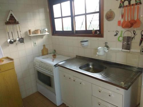 a small kitchen with a sink and a stove at Chalé Lady in Campos do Jordão