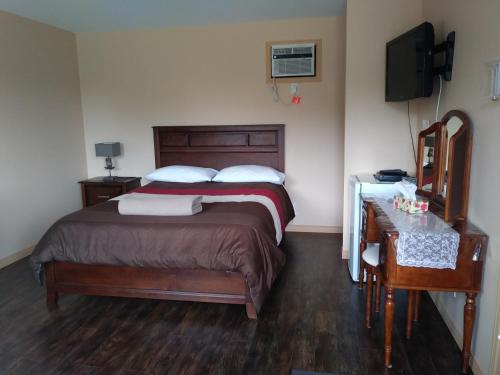 a bedroom with a bed and a desk and a television at Motel la Maison de Travers in Baie-Sainte-Catherine