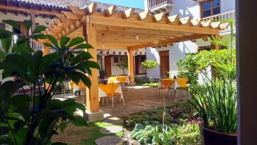 a wooden pergola in a garden with tables and chairs at Hotel Santa Clara in San Cristóbal de Las Casas