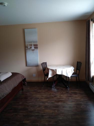 a room with a table and two chairs and a bed at Motel la Maison de Travers in Baie-Sainte-Catherine