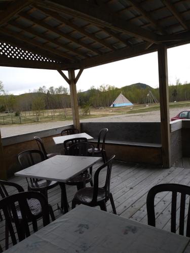 a patio with tables and chairs and a view of a field at Motel la Maison de Travers in Baie-Sainte-Catherine
