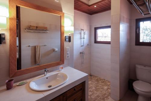 a bathroom with a sink and a toilet and a mirror at Murni's Houses & Spa in Ubud
