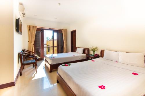 a bedroom with two beds and a desk with a piano at Golden River Hotel in Hoi An