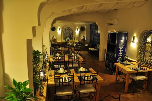 um restaurante com mesas e cadeiras num quarto em Hotel Al Alba Hammam & Restaurant em Arzila