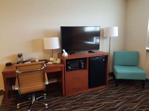 a hotel room with a desk with a television and a chair at Best Western Plus Durham Hotel & Conference Centre in Oshawa