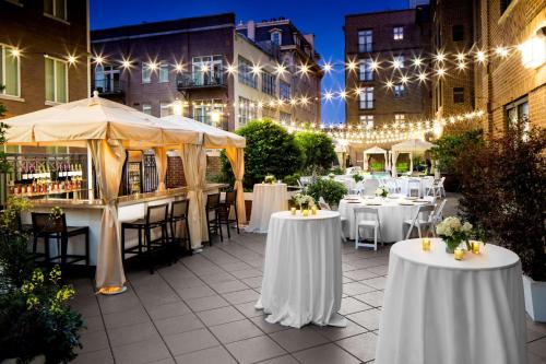 a patio with white tables and chairs and lights at Andaz Savannah, By Hyatt in Savannah