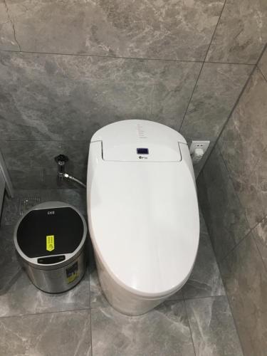 a white toilet in a bathroom with a trash can at Beijing Downtown Travelotel in Beijing