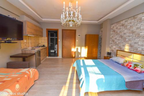 a bedroom with a large bed and a chandelier at Menios Apartments and Studios in Nea Kalikratia