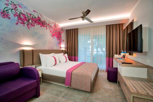 a hotel room with a bed and a purple couch at Pirate's Beach Club in Tekirova