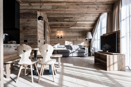 a living room with two white chairs and a television at Chalet Cogolara in Colfosco