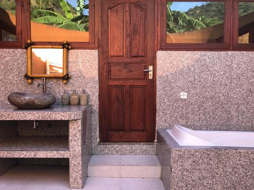 a bathroom with a sink and a tub and a door at Good Karma Bungalows in Amed