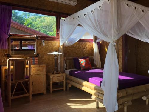 a bedroom with a bed with a canopy at Good Karma Bungalows in Amed