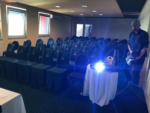 a man standing in a room with a table and chairs at Hotel Staccato in Prijedor
