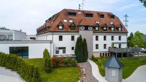 a large white building with a red roof at Hôtel Restaurant Les Alizés in Lipsheim
