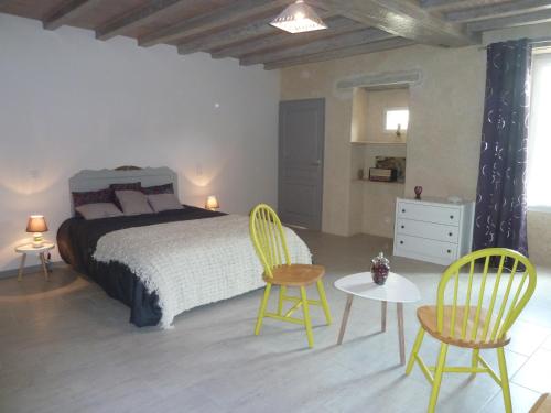 1 Schlafzimmer mit einem Bett, 2 Stühlen und einem Tisch in der Unterkunft LES 3 PETITS COCHONS in Le Bouchet