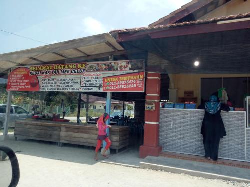 a woman is standing outside of a restaurant at Syahril homestay in Dungun