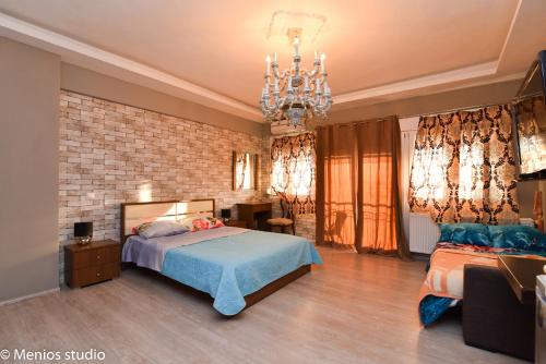 1 dormitorio con cama y lámpara de araña en Menios Apartments and Studios, en Nea Kalikratia