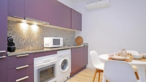 a kitchen with purple cabinets and a table with a microwave at Cambrils 4 in Cambrils