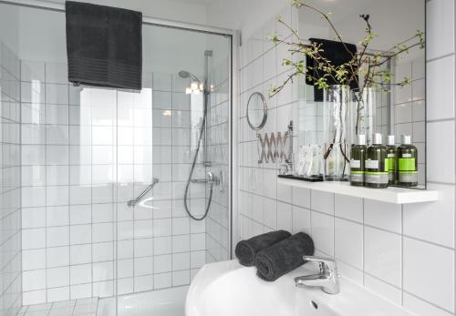 a white tiled bathroom with a sink and a shower at Hotel Stadt Hamburg in Bad Salzuflen