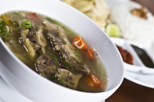 a white bowl of soup on a plate at Neo Hotel Tendean Jakarta by ASTON in Jakarta