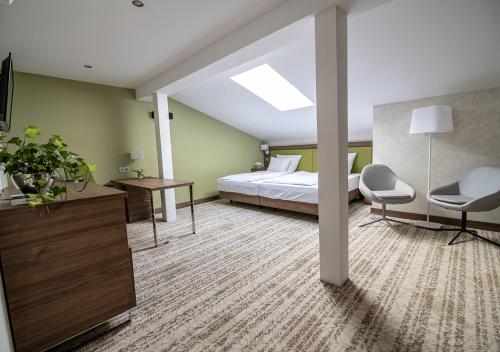 1 dormitorio con 1 cama, escritorio y sillas en Hotel Roma, en Kalisz