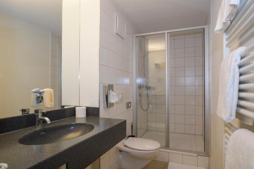 ein Bad mit einem Waschbecken, einem WC und einer Dusche in der Unterkunft JUFA Hotel Wangen im Allgäu in Wangen im Allgäu