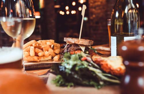 a table with a sandwich and french fries and a glass of wine at Nomads Sydney in Sydney