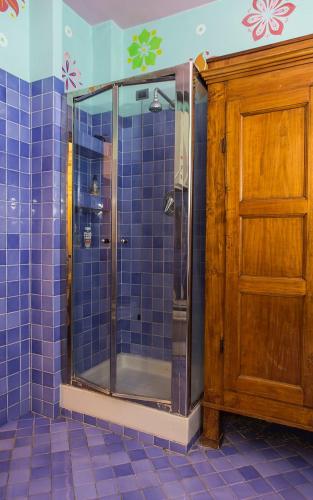 uma casa de banho com um chuveiro com azulejos azuis e uma porta de madeira em University beb bologna em Bolonha