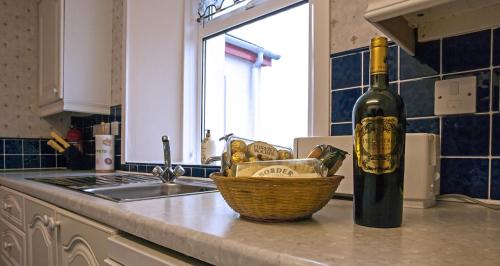 - une bouteille de vin et un panier sur un comptoir de cuisine dans l'établissement Airdaniar Cottage, à Applecross