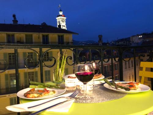 - une table avec deux assiettes de pizza et un verre de vin dans l'établissement Chez Kari-top location in charming old town, à Nice