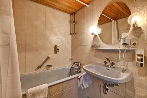 uma casa de banho com um lavatório, uma banheira e um espelho. em Hotel Lamm em Weinstadt