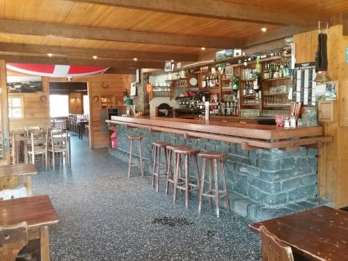 un restaurant avec un bar avec des tabourets et des tables dans l'établissement Hotel Restaurant Les Rosieres, à Manigod