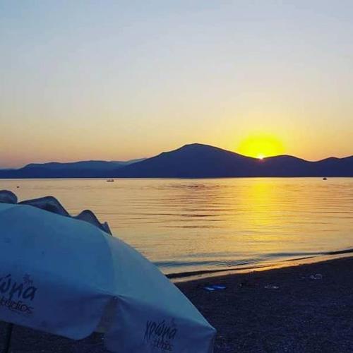 a sunset on the beach with the sun setting over the water at Chroma Studios in Oreoí