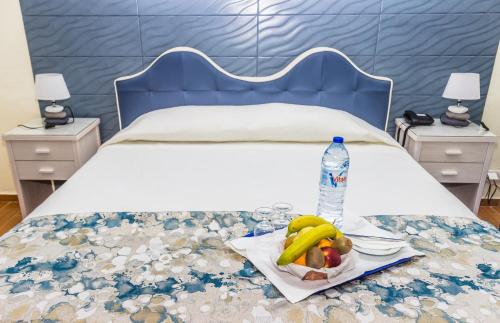 a bed with a plate of fruit and a bottle of water at Aeromar Beach Hotel in Faro