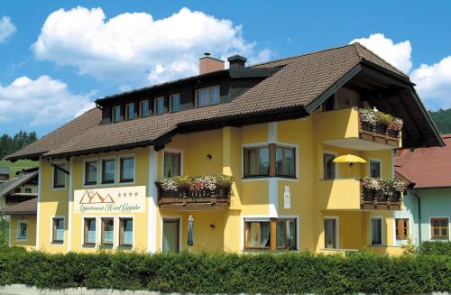 a yellow building with flower boxes on it at Aktiv- und Wellnesshotel Gutjahr in Abtenau