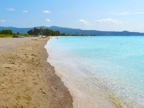a sandy beach with people swimming in the water at Chroma Studios in Oreoí