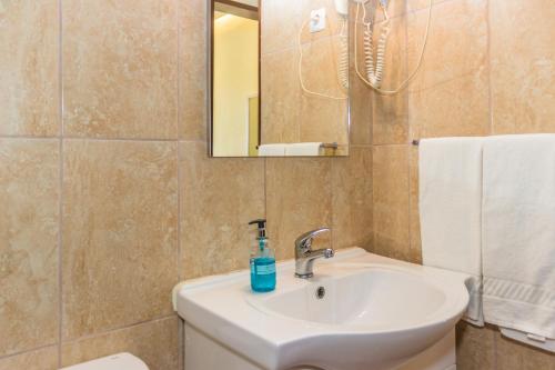 a bathroom with a sink and a toilet and a mirror at Aeromar Beach Hotel in Faro
