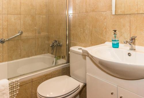 a bathroom with a toilet and a sink and a tub at Aeromar Beach Hotel in Faro