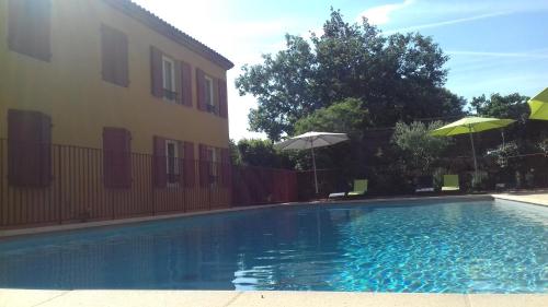 a swimming pool in front of a building with umbrellas at Résid'Artel Cadarache - ITER in Saint-Paul-lez-Durance